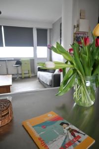 eine Vase mit Blumen auf einem Tisch mit einer Zeitschrift in der Unterkunft Chez Maïse - CR CONCIERGERIE in Dunkerque