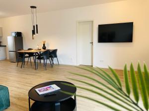 a living room with a table and a tv on the wall at LIGHTPLACE - Moderne Apartments in Braunschweig - Balkon - Netflix - Am Kanal in Braunschweig