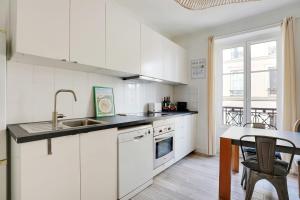 a kitchen with white cabinets and a sink and a table at OBERKAMPF - BASTILLE Charming apartment in Paris