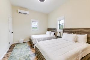 two beds in a bedroom with white walls and wooden floors at Abbeville Cabin on 450 Acres Near Lake Eufaula! in Abbeville