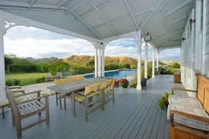 a deck with a wooden table and chairs on a house at Cape South Estate - International award-winning country estate with Pacific views in Havelock North