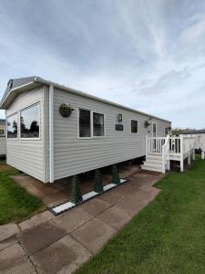 Une petite maison blanche dans une cour dans l'établissement 3 Bedroom Stylish Caravan - Vans With Business Sign Not Allowed, à Port Seton