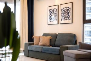 een woonkamer met een blauwe bank en foto's aan de muur bij Comfy 3BR Apt in Danga Bay FREE Parking Sea View in Johor Bahru