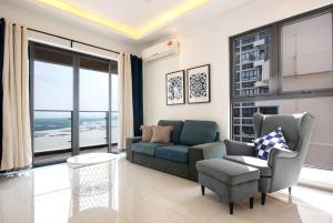 een woonkamer met een bank en een stoel bij Comfy 3BR Apt in Danga Bay FREE Parking Sea View in Johor Bahru