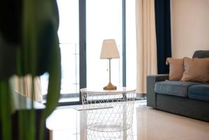 een woonkamer met een bank en een tafel met een lamp bij Comfy 3BR Apt in Danga Bay FREE Parking Sea View in Johor Bahru +29 foto's