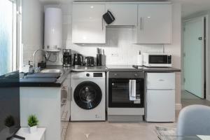 a kitchen with a washing machine and a microwave at Chic 1BR Gem, Croydon Central in Croydon
