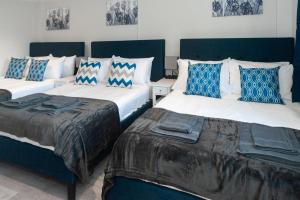 two beds in a room with blue and white pillows at Chic 1BR Gem, Croydon Central in Croydon