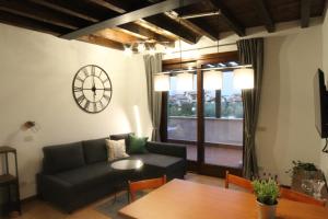 een woonkamer met een bank en een klok aan de muur bij Lagosuite in Peschiera del Garda