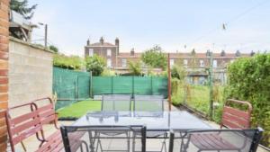 a patio with a table and chairs and a tennis court at Spacieuse maison avec chambres et salle de bain privées en colocation à 10 min de Lille in Lille