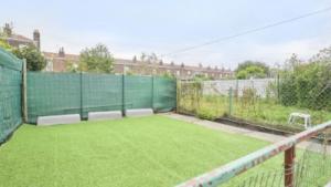 a tennis court with a green fence and grass at Spacieuse maison avec chambres et salle de bain privées en colocation à 10 min de Lille in Lille +3 photos