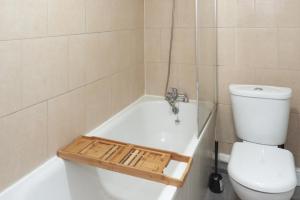 a bathroom with a toilet and a bath tub with a sink at Chic 1BR Gem, Croydon Central in Croydon