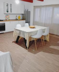 a dining room table with white chairs and a kitchen at Apartamento Casa Rosabella in Caleta de Sebo