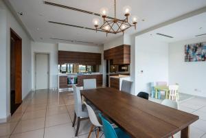 ein Esszimmer und eine Küche mit einem Holztisch und Stühlen in der Unterkunft A Lux & Cozy 4BR Penthouse with Harbour Views in Nusajaya