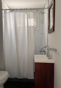 Un baño con una cortina de ducha blanca y un lavabo. en Depto con vistas, en San Nicolás de los Arroyos