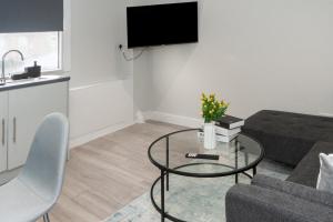 uma sala de estar com um sofá e uma mesa de vidro em Modern 1BR Haven Central Croydon em Croydon