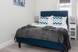 um quarto com uma grande cama azul com almofadas em Modern 1BR Haven Central Croydon em Croydon