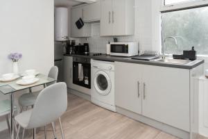 uma cozinha branca com um lavatório e uma máquina de lavar roupa em Modern 1BR Haven Central Croydon em Croydon