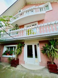 a pink house with a balcony and plants at Pensiune Perla Dunarii in Giurgiu