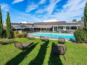 - un groupe de chaises assises dans l'herbe au bord de la piscine dans l'établissement Novotel Reims Tinqueux, à Reims