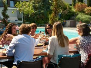 un groupe de personnes assises autour d'une table en train de boire du vin dans l'établissement Novotel Reims Tinqueux, à Reims