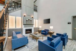 a living room with blue chairs and a fireplace at Best Western Plus First Coast Inn and Suites in Yulee