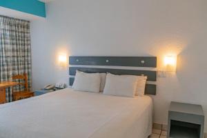 a bedroom with a white bed with two pillows at La Concha Beach Hotel & Club in La Paz