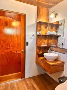 baño con lavabo y puerta de madera en Hotel Trópico Monteverde, en Monteverde