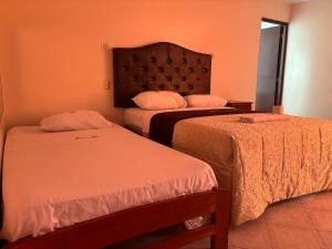 2 camas en una habitación con paredes de color naranja en Hospedaje San Blas en Lima