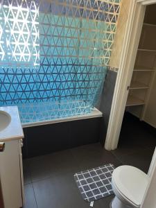 a bathroom with a toilet and a blue tile wall at Hostal Casona del Mar in Viña del Mar