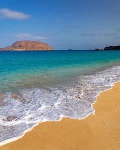 a beach with the ocean and mountains in the background at Apartamento Casa Rosabella in Caleta de Sebo