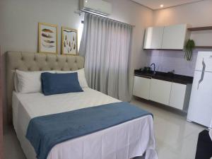 a bedroom with a large bed with a blue pillow at apartamento studio setor Sul in Palmas