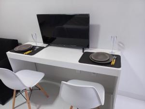 a desk with a computer monitor and two chairs at apartamento studio setor Sul in Palmas