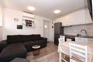 ein Wohnzimmer mit einem schwarzen Sofa und einer Küche in der Unterkunft Pločica in Ploče