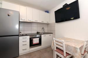 eine Küche mit einem Kühlschrank, einem Tisch und einem TV in der Unterkunft Pločica in Ploče