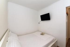 a small white room with a bed and a flatscreen tv at Pločica in Ploče