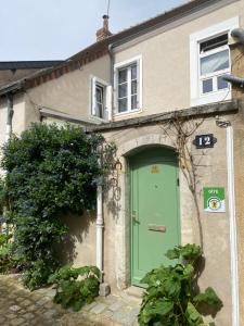 una casa con una puerta verde delante de ella en La Maison KDO, en Châteauroux