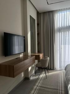 1 dormitorio con TV, silla y escritorio en Garden & Pool Access Studio en Sharjah