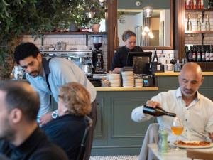 eine Gruppe von Menschen, die an einem Tisch in einem Restaurant sitzen in der Unterkunft Hotel Indigo London Hyde Park Paddington, an IHG Hotel in London