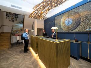 un groupe d'hommes debout à un comptoir dans une pièce dans l'établissement Hotel Indigo London Hyde Park Paddington, an IHG Hotel, à Londres