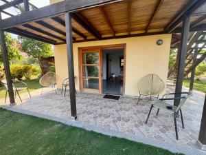 eine Terrasse mit Stühlen und ein Haus in der Unterkunft Juanchos House Hostel Tayrona in Los Naranjos