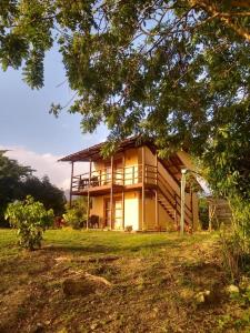 ein großes Haus mit einer Veranda auf einem Rasen in der Unterkunft Juanchos House Hostel Tayrona in Los Naranjos