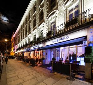 a street at night with tables and chairs in front of a building at Hotel Indigo London Hyde Park Paddington, an IHG Hotel in London