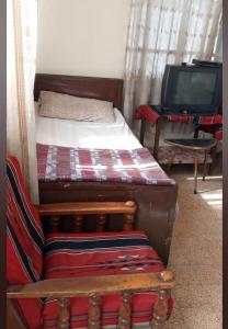 a bedroom with two beds and a couch and a tv at Al Amawi Hostel in Amman