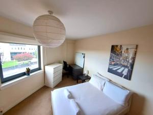 um quarto com uma cama branca e uma janela em Modern 2 Bed Apartment Close to Gla Airport & M8 em Paisley