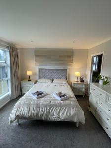 a bedroom with a large bed with two tables and two lamps at Private Ensuite with Spa in Upper Hutt in Upper Hutt