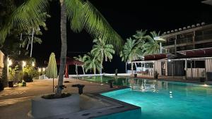 a swimming pool with a palm tree in front of a building at South Cape Beach Resort in San Juan
