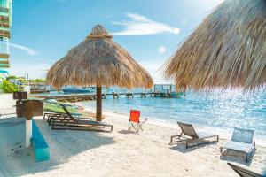 a beach with chairs and a straw umbrella and the water at Edgewater Lodge in Layton
