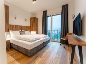 Dormitorio con cama, escritorio y TV en Ibex panorama Lodge en Turracher Hohe