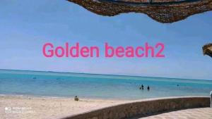 a beach with people in the water and the words golden beach at Golden Beach 2 RasSudr in Al Ḩafāʼir +5 photos