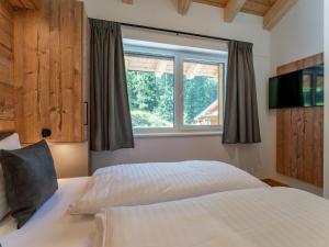 a bedroom with a white bed and a window at Alpinchique 3 Mountain Chalet in Turracher Hohe